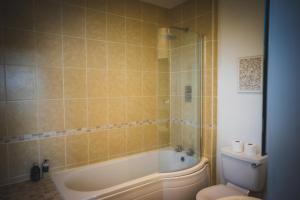 a bathroom with a bath tub and a toilet at Heatherfield House in Oban