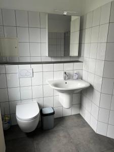 ein Badezimmer mit einem Waschbecken, einem WC und einem Spiegel in der Unterkunft Dill Apartments Peine in Peine