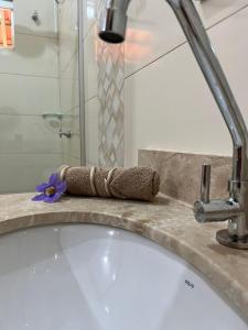 baño con bañera y lavabo con una flor púrpura en Pousada Canela de Ema en Mateiros