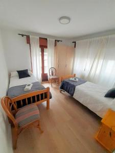 a bedroom with two beds and a table and a chair at Pensión Río Umia in Caldas de Reis