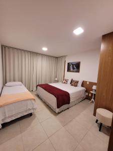 a hotel room with two beds and a desk at VILLAGE DAS ACÁCIAS NO PISCINAS NATURAIS in Mata de Sao Joao