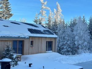 una casa con un pannello solare sul tetto nella neve di Ferienhäuser Gruber-List a Sankt Corona am Wechsel