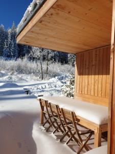 um gazebo de madeira com um banco coberto de neve em Ferienhäuser Gruber-List em Sankt Corona am Wechsel