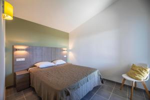 a bedroom with a bed and a table and a chair at Résidence Santa Monica in Bonifacio