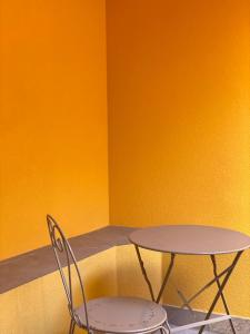 a table and two chairs in front of a yellow wall at Casimiro Home in Cesena