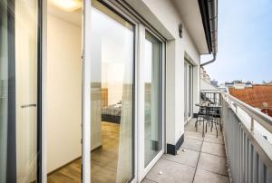 einen Balkon mit Glasschiebetüren und Blick auf ein Schlafzimmer in der Unterkunft Jimmy's Apartments Lory in Wien