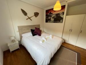 - une chambre avec un grand lit blanc et des oreillers dans l'établissement HONDARGANE, en las playas de Laga y Laida., à Ibarrangelu