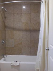 Sun Star Inn في لوس بانوس: حمام مع حوض استحمام ودش مع ستارة الدوش