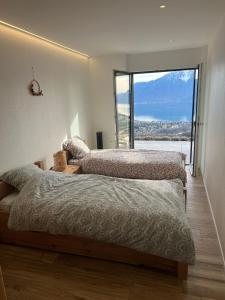 two beds in a bedroom with a large window at Appartement 180 degrés de rêve à Jongny in Jongny