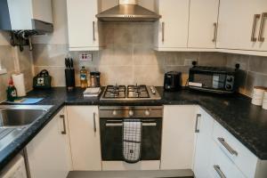 a kitchen with a stove and a microwave at 63 Westmorland St by Prestige Properties SA in Barrow in Furness