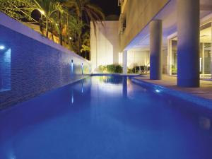 a swimming pool in a building at night at Oaks Townsville Metropole Hotel in Townsville