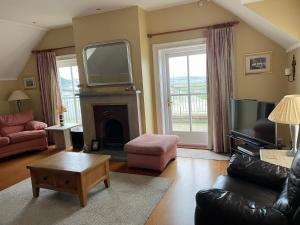 a living room with a tv and a couch and a fireplace at Causeway Lodge in Aird