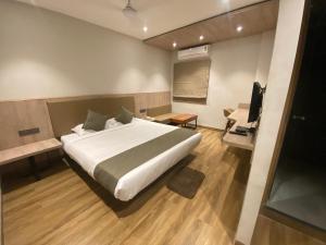 PānchuriaにあるFirangipani Suites - A Corporate Boutique Hotelのベッドルーム(大型ベッド1台、テレビ付)