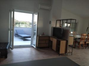 uma sala de estar com uma televisão e uma porta de vidro deslizante em Apartment Ivano em Fažana