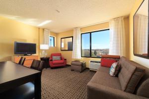 a living room with a couch and chairs and a television at TownePlace Suites Farmington in Farmington