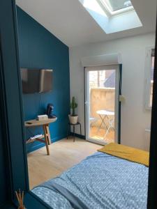 a bedroom with a blue wall with a bed and a window at Le cocon amiénois in Amiens
