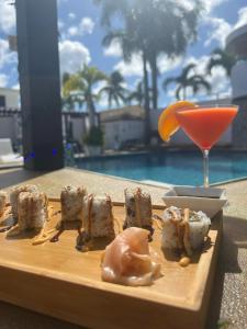 a plate of sushi and a drink next to a pool at Aqua Marina Beach Club in Rincon
