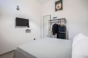 ein weißes Schlafzimmer mit einem Bett und einem TV in der Unterkunft Two Bedrooms Apt in Sorrento Center with Terrace in Sorrent