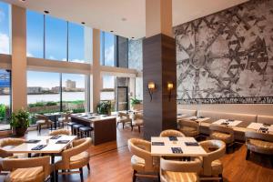 um restaurante com mesas e cadeiras e janelas grandes em Sheraton Norfolk Waterside Hotel em Norfolk