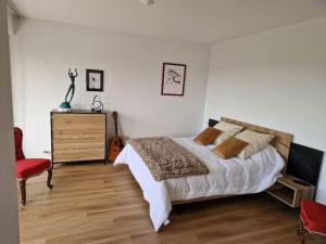 um quarto com uma cama, uma cadeira e uma guitarra em Au Beau Voyage à 2 pas des Thermes em Thonon-les-Bains