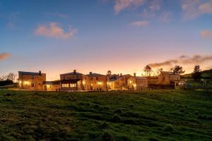 a large house in a field at sunset at O Viso Ecovillage - Hotel Ecologico Vegano in Orol