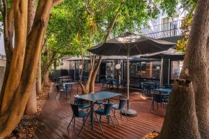 een houten terras met tafels, stoelen en bomen bij Hotel do Carmo in Funchal