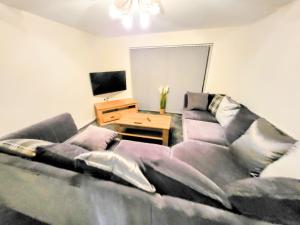 a large couch in a living room with a television at Large Modern House with Private Parking in Heeley