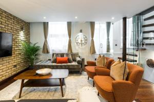 ein Wohnzimmer mit orangefarbenen Stühlen und einem Sofa in der Unterkunft Knightsbridge Harrods 2 Bedrooms, 3 Beds, 2.5 Bath in London
