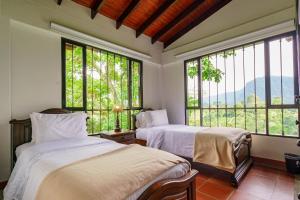 two beds in a room with large windows at Acaima Café Lodge in Sasaima