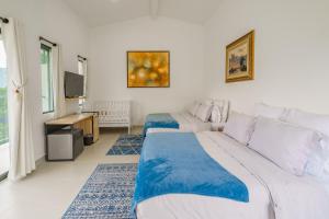 a bedroom with two beds and a television in it at Acaima Café Lodge in Sasaima