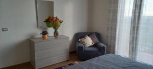 Un dormitorio con una silla y un tocador con un jarrón de flores en Rosa's House Bed and Breakfast en Santa Margherita di Belice