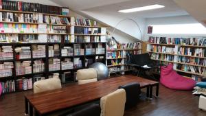a library with a table and chairs and books at Warak Guesthouse in Jeju