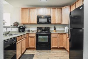 una cocina con armarios de madera y electrodomésticos negros en MVC - Sweet Penthouse, en Pigeon Forge