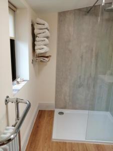 ein Bad mit Dusche und Handtüchern an der Wand in der Unterkunft Lion Hotel in Llanbister