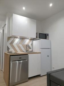 une cuisine avec des armoires blanches et un appareil en acier inoxydable dans l'établissement Cocon à la campagne - Disney 20 min - Paris 40 min - 2 terrasses, à Dammartin-sur-Tigeaux