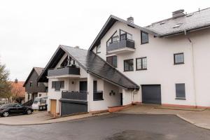 Biały dom z samochodem zaparkowanym na parkingu w obiekcie Wohnung Hirschhöhe im Taunus w mieście Neu-Anspach