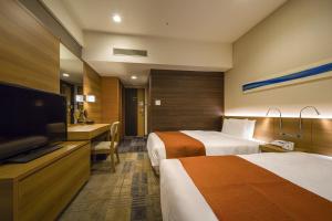 a hotel room with two beds and a flat screen tv at Hotel Sunroute Chiba in Chiba