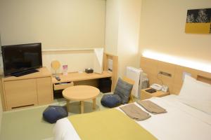 a bedroom with a bed and a desk with a television at Hotel Sunroute Chiba in Chiba
