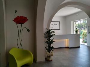 a room with a green chair and a red rose at Hotel La Smorfia in Castiglioncello