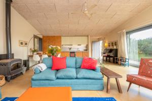 sala de estar con sofá azul y almohadas rojas en La casita del bosque, en Vilopríu