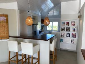 - une cuisine avec un bar doté de chaises blanches et de lumières dans l'établissement Villa at secured gated resort near Mambo Beach!, à Willemstad