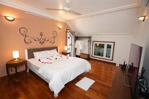 a bedroom with a large white bed and a television at Musketeers Guest House in Hanoi