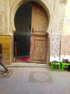 una persona che passa davanti a una grande porta di legno in un edificio di riad zahra a Fes