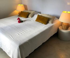 - un lit blanc avec deux lampes et des fleurs dans l'établissement Villa at secured gated resort near Mambo Beach!, à Willemstad