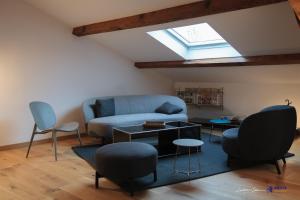 ein Wohnzimmer mit einem Sofa, Stühlen und einem Dachfenster in der Unterkunft Jardin des Anges - Castillet view - WIFI- Centre ville in Perpignan