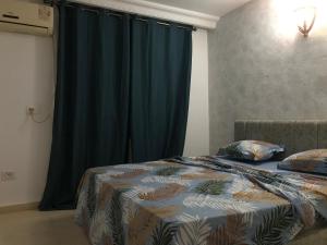 1 dormitorio con cama y cortina azul en Dar Slima, en Aghīr