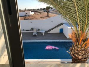 a pink pig swimming in a pool next to a house at Dar Slima in Aghīr