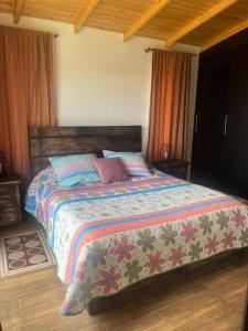 a bedroom with a bed with a colorful comforter at Cabaña Campestre Montreal in Paipa