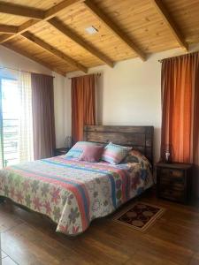 1 dormitorio con cama y techo de madera en Cabaña Campestre Montreal, en Paipa