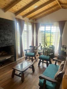 a living room with chairs and a table and a fireplace at Cabaña Campestre Montreal in Paipa